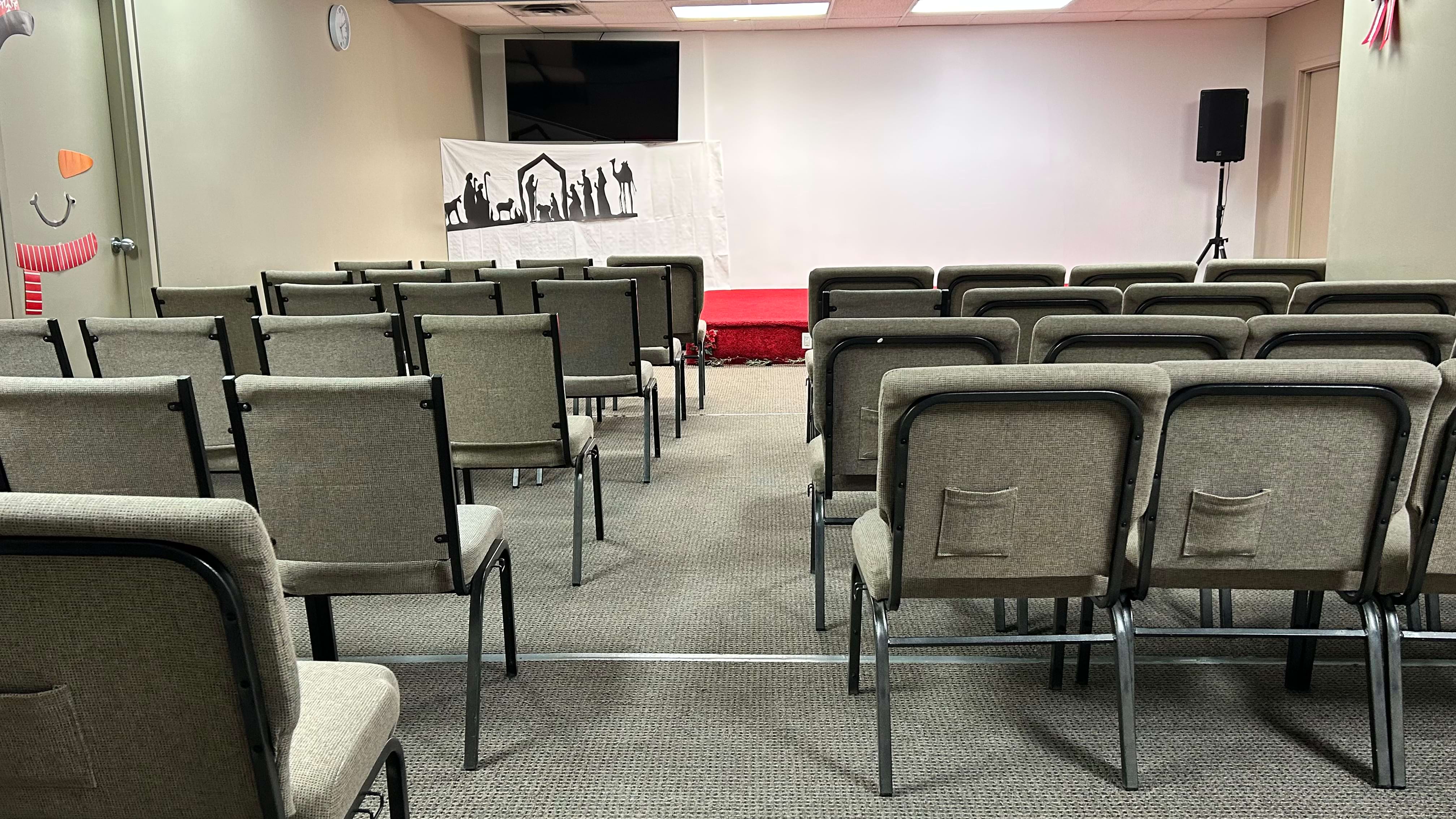 Empty conference room with rows of chairs facing a stage with a white banner background.