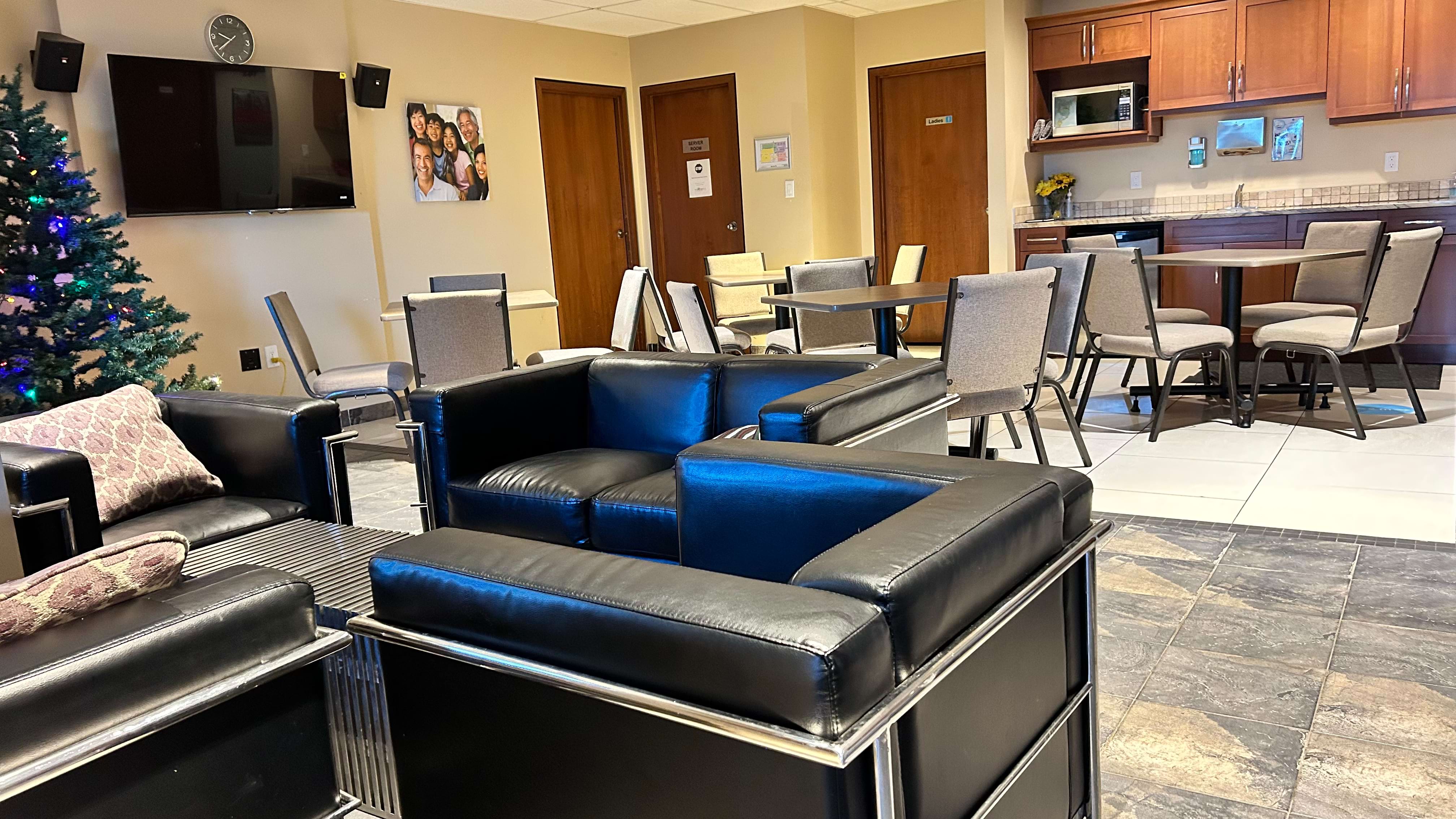 Modern waiting area with black and blue sofas, chairs, and a kitchenette.