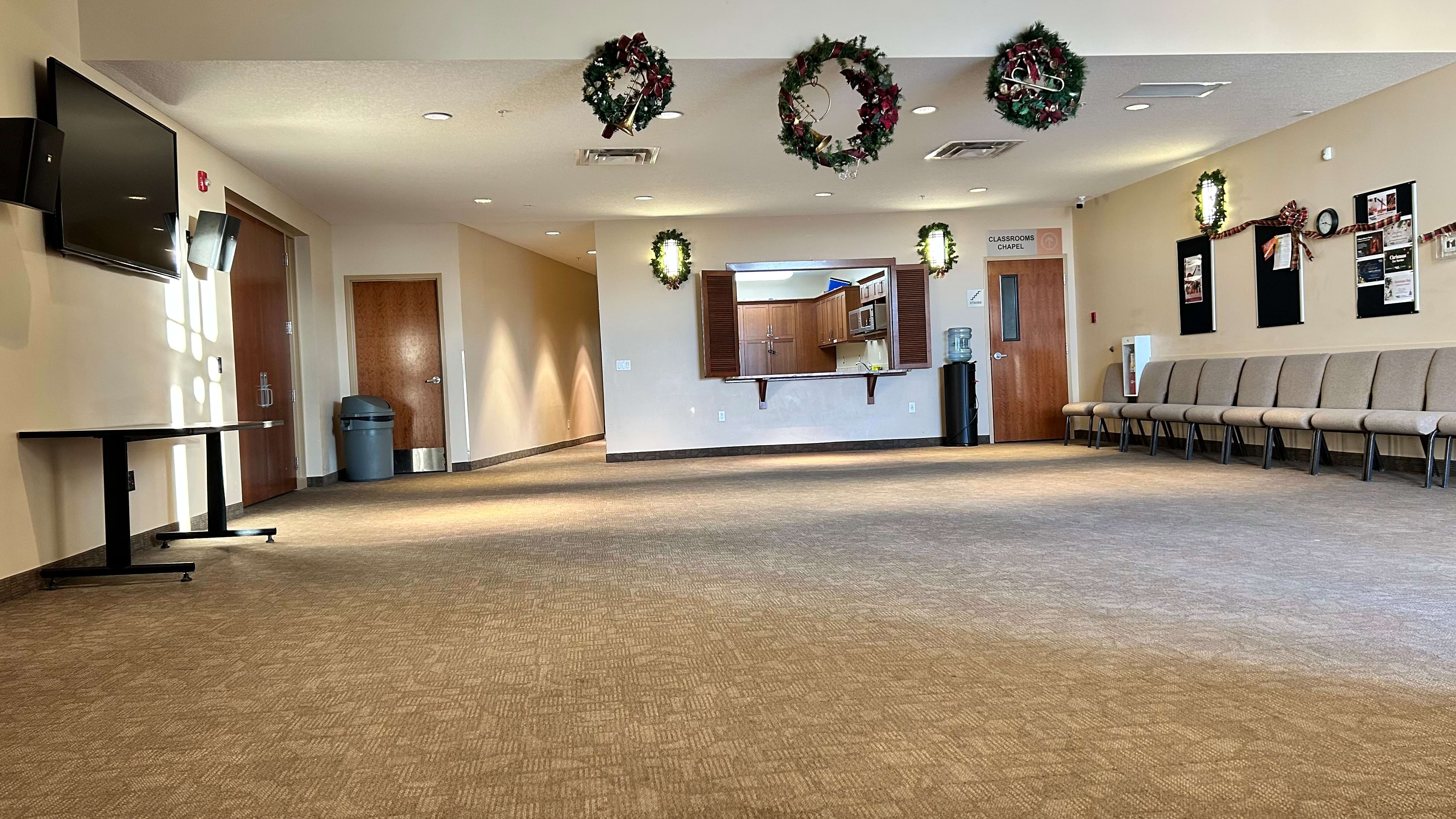 Spacious lobby with chairs lined against a wall and holiday wreaths hanging above.